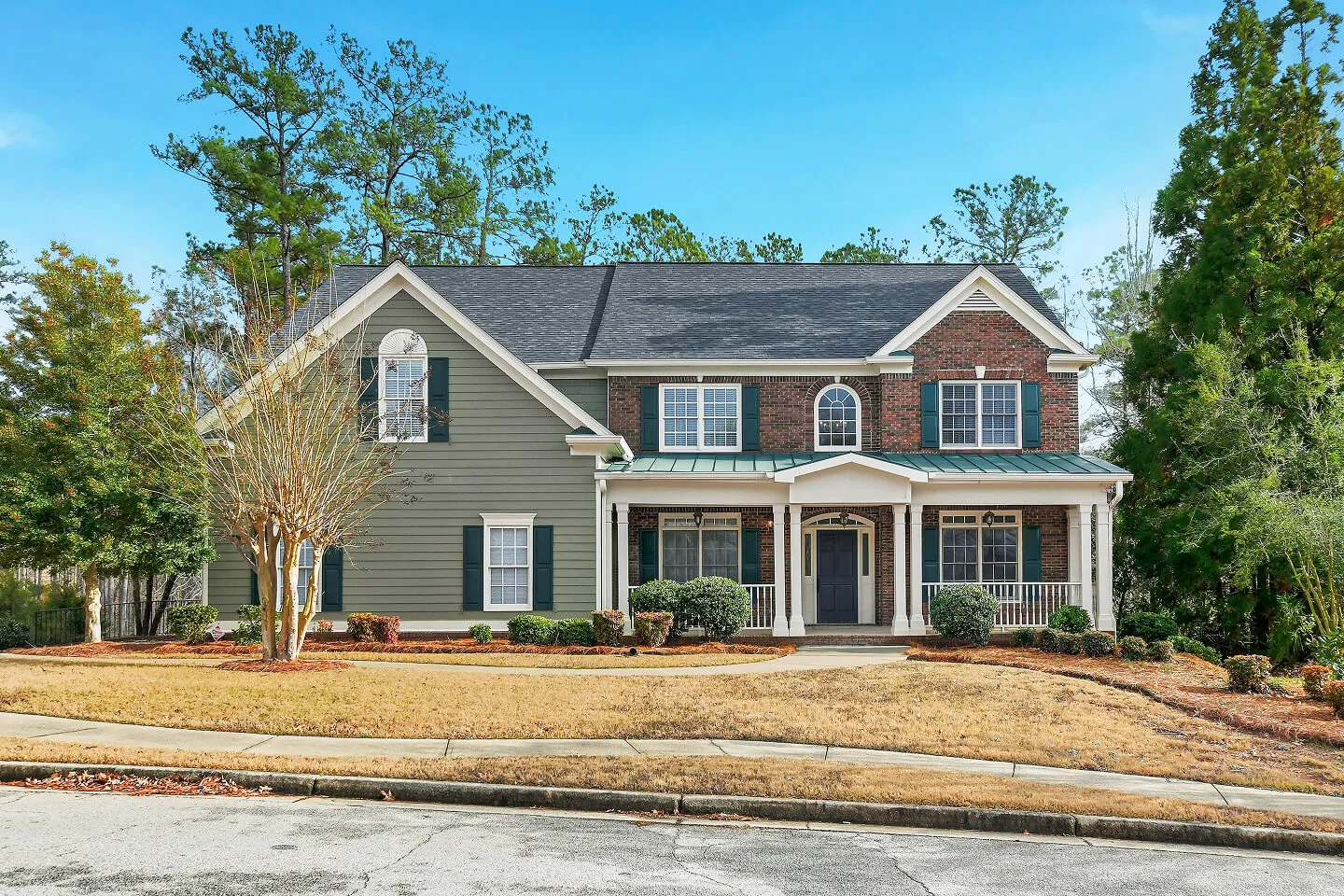 Two-story suburban home exterior with front porch and landscaped yard photographed by Blue Dot Photos